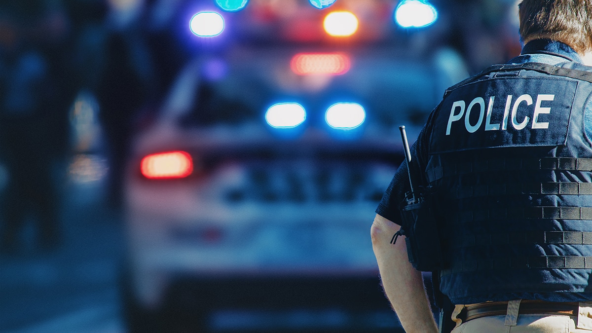 a police officer and police vehicle with its lights on