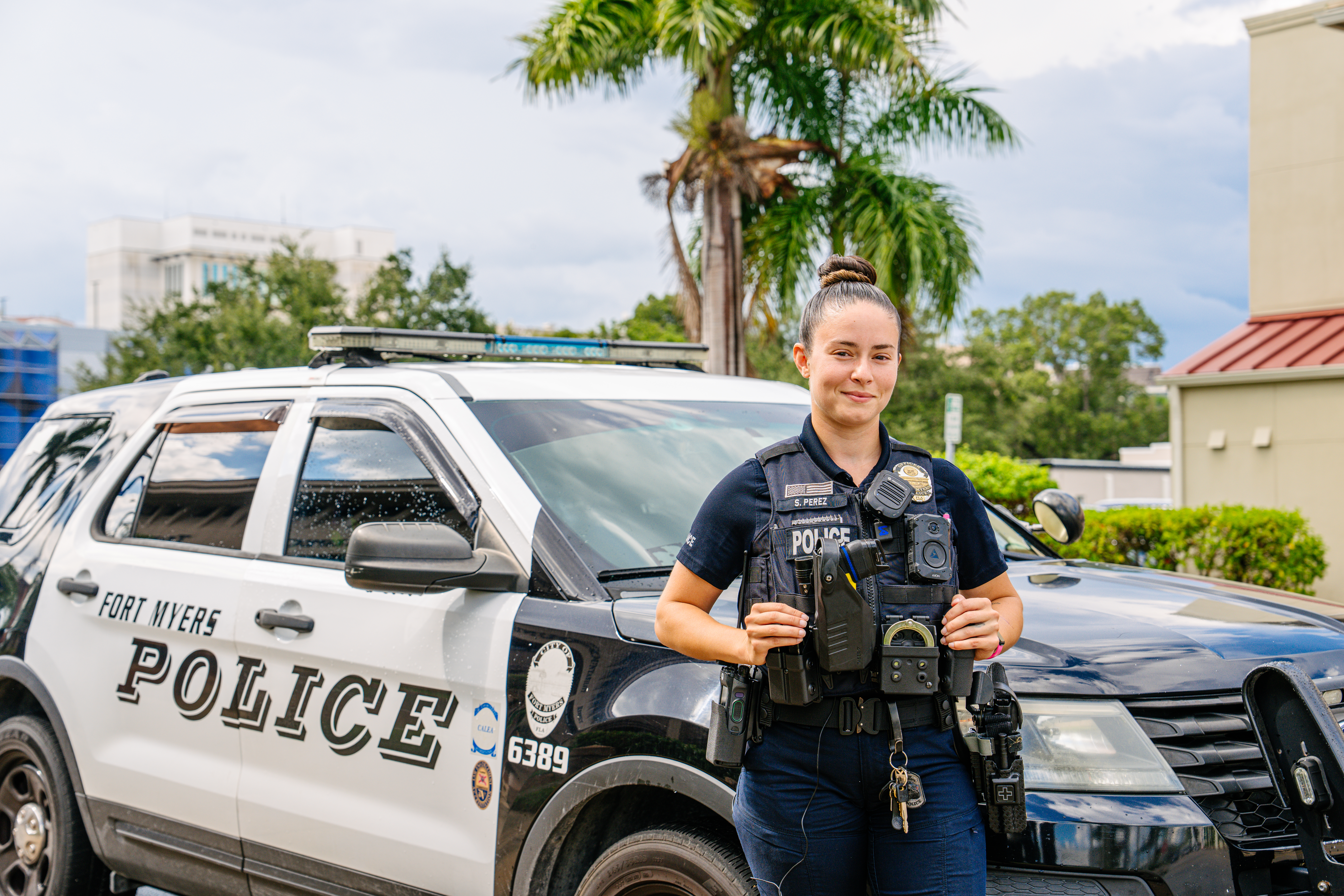 a police officer smiling standing by their vehicle