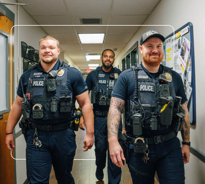 three police officers walking in a hallway and smiling