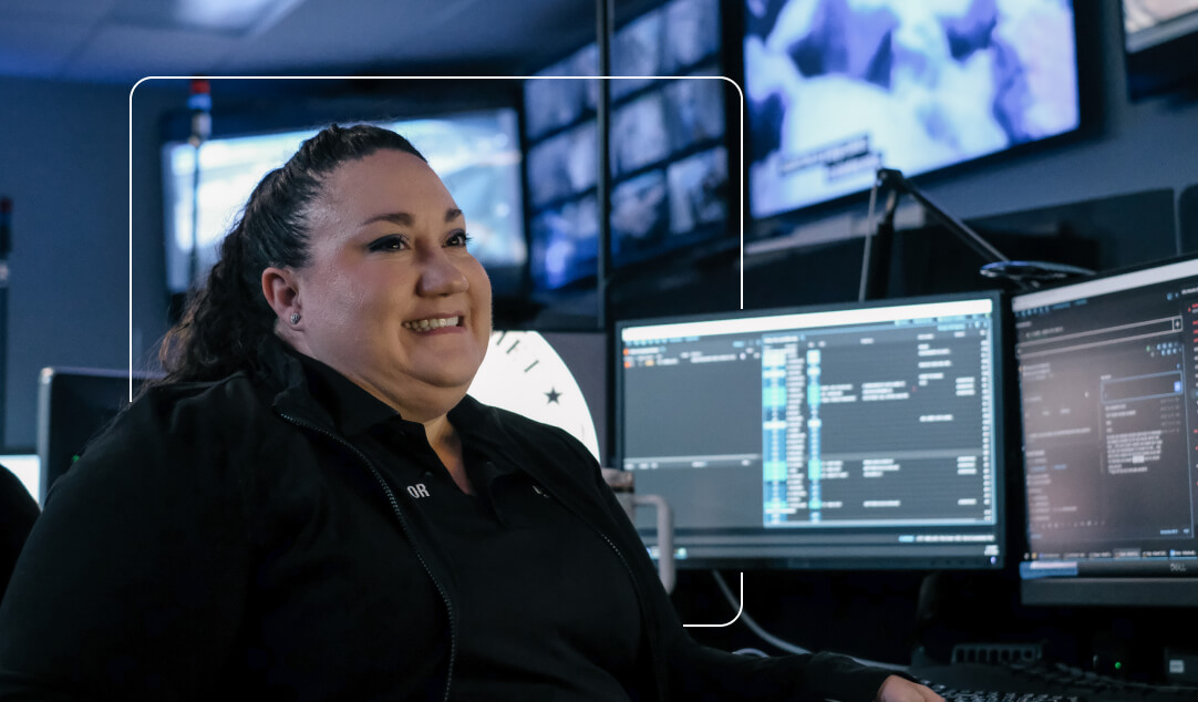 Mark43-Resources-Learn@2x-2-1 Female operator smiling and sitting by her computer screens