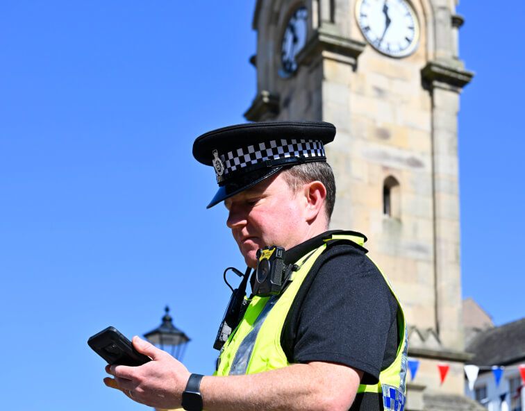 a male British police officer using a smart phone