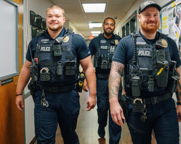 three police officers walking together in a hallway and smiling