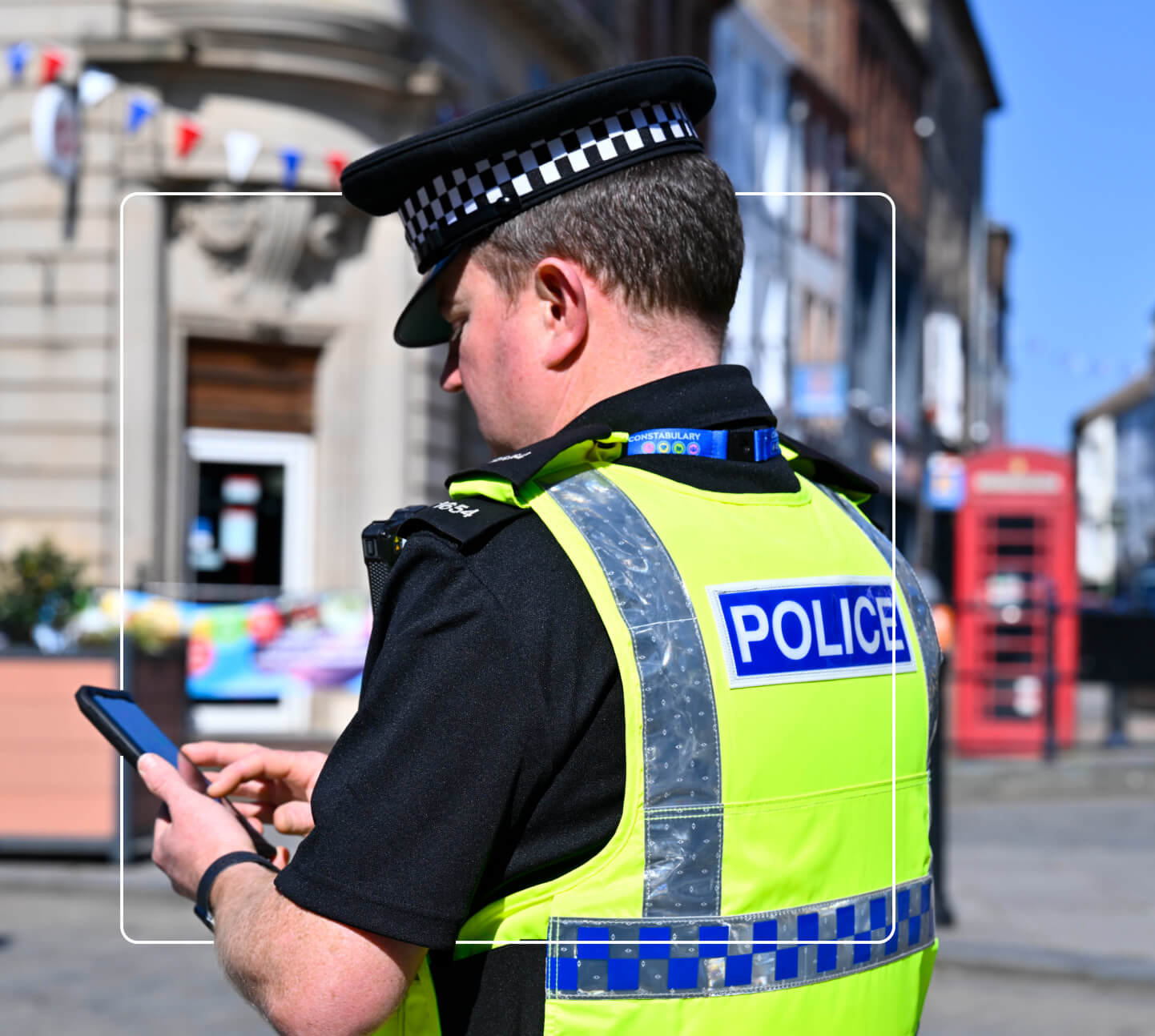 a male British police officer using a smart phone