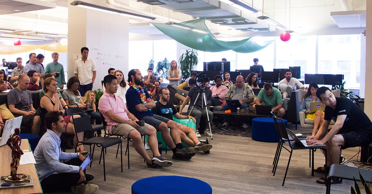 a full office of people gathered for a meeting and presentation